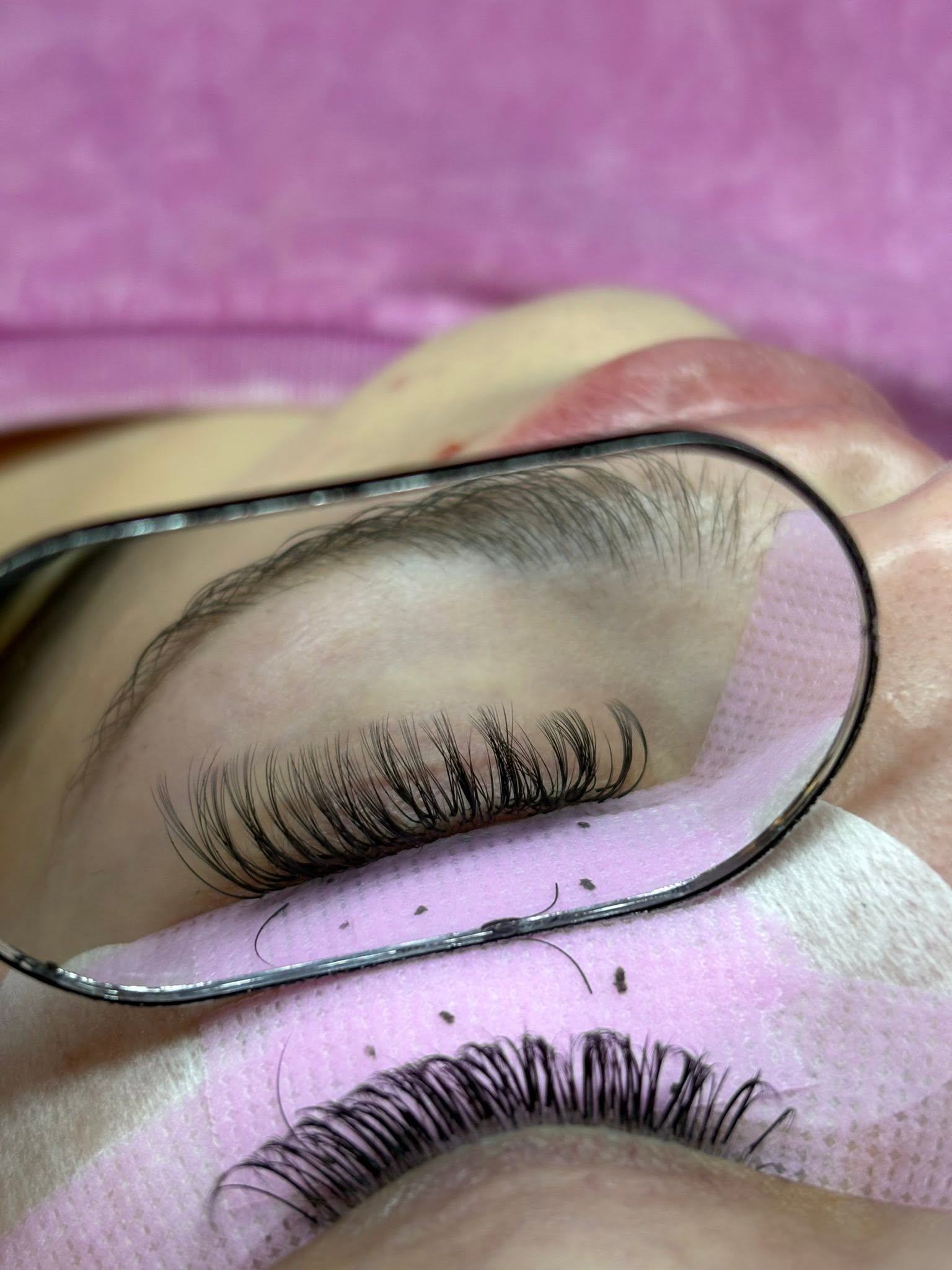Close-up of a classic lash extension set by Ellie, shown in a stylist's mirror